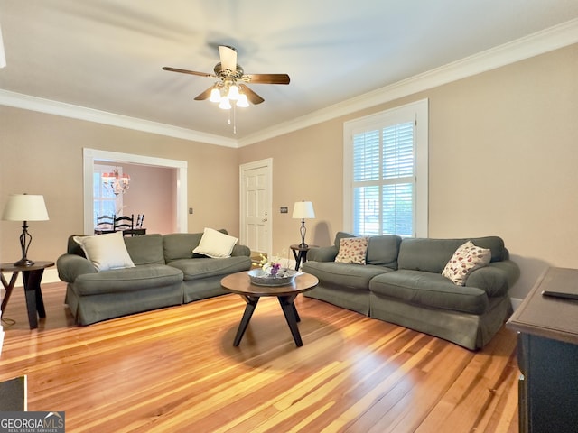 living room featuring ornamental molding, light wood finished floors, and ceiling fan with notable chandelier