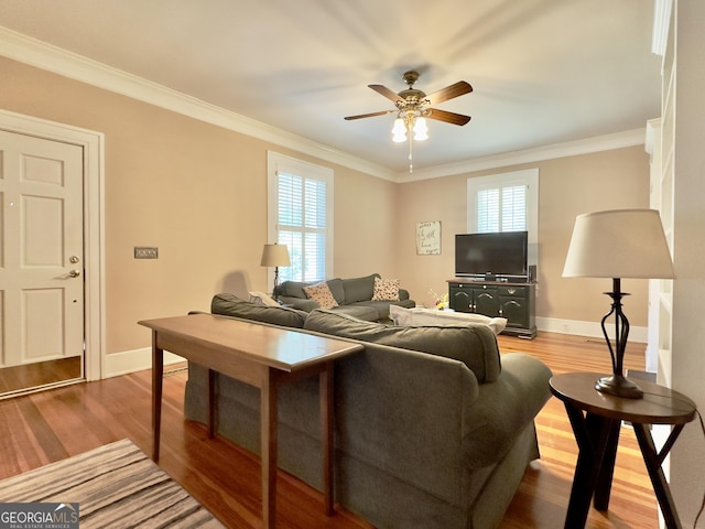 living area with ceiling fan, ornamental molding, and wood finished floors