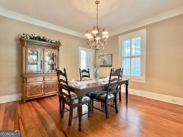 dining area featuring crown molding, baseboards, wood finished floors, and a chandelier