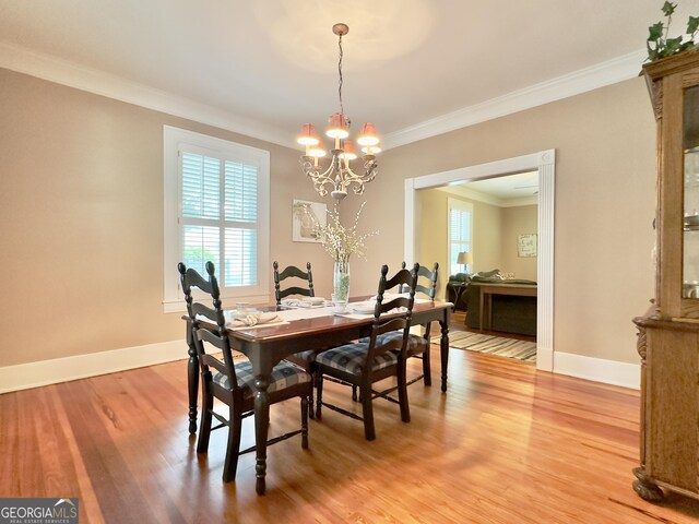 dining space with crown molding, an inviting chandelier, a healthy amount of sunlight, and light wood-style floors