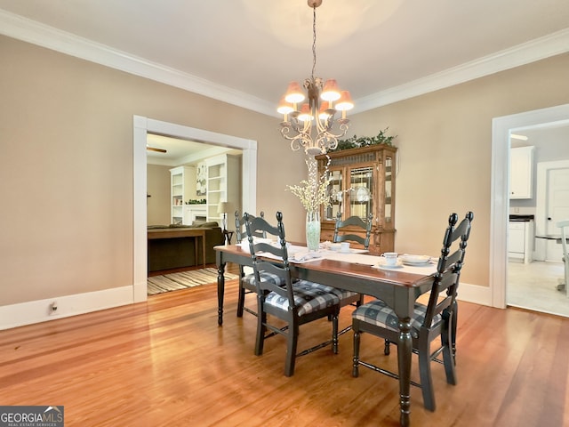 dining space with baseboards, ornamental molding, light wood-style flooring, and a notable chandelier