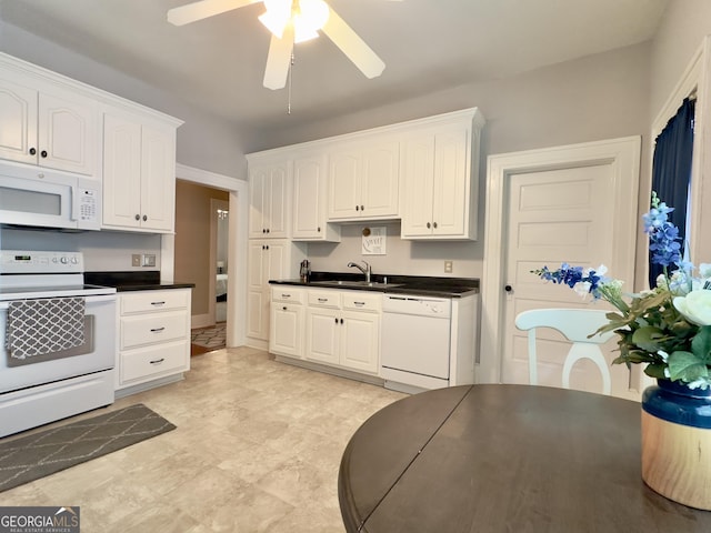kitchen with a ceiling fan, dark countertops, white appliances, white cabinets, and a sink