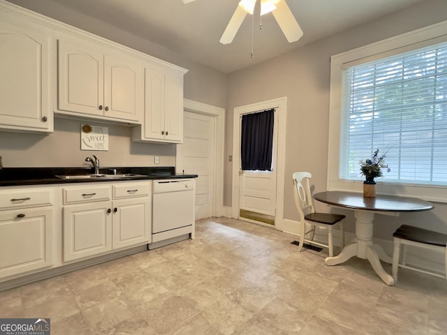 kitchen featuring a ceiling fan, dark countertops, white dishwasher, white cabinetry, and a sink