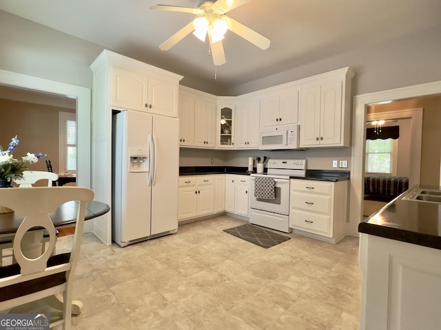 kitchen with dark countertops, white appliances, glass insert cabinets, ceiling fan, and white cabinetry