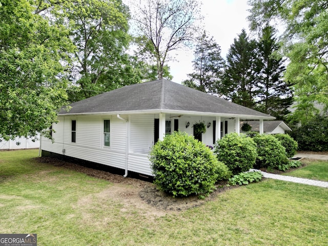 view of side of home with roof with shingles and a yard
