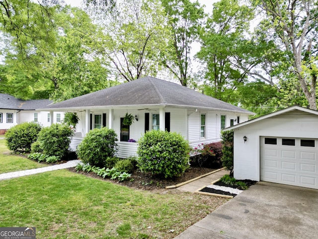ranch-style home featuring covered porch, a front yard, roof with shingles, an outbuilding, and driveway