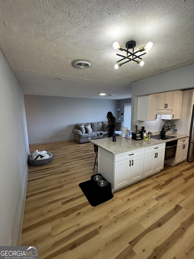 2461 Mcalpin Ter, East Point, GA 30344 - kitchen featuring a textured ceiling, light wood-style flooring, white cabinets, a chandelier, and open floor plan