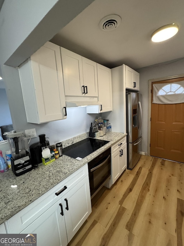 2461 Mcalpin Ter, East Point, GA 30344 - kitchen with oven, stainless steel refrigerator with ice dispenser, black electric stovetop, under cabinet range hood, and white cabinets