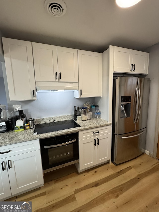 2461 Mcalpin Ter, East Point, GA 30344 - kitchen with stainless steel fridge with ice dispenser, oven, under cabinet range hood, black electric cooktop, and light wood-style flooring