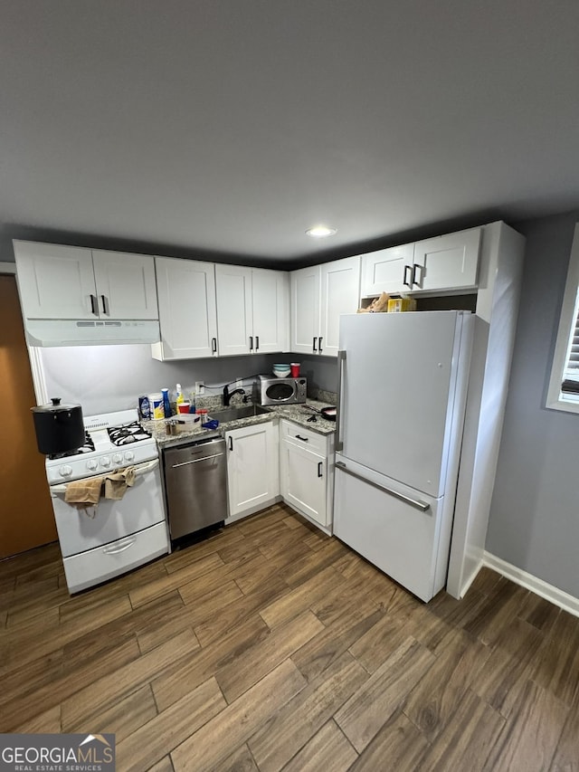 2461 Mcalpin Ter, East Point, GA 30344 - kitchen with stainless steel appliances, under cabinet range hood, dark wood-type flooring, white cabinetry, and light stone countertops