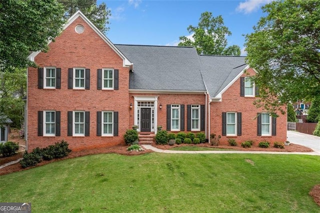 view of front facade with brick siding and a front yard