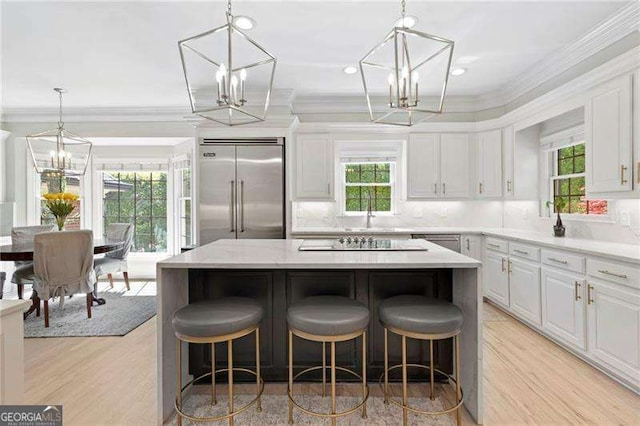 5790 Heards Forest Dr, Atlanta, GA 30328 - kitchen with black electric stovetop, a chandelier, light wood-style flooring, a kitchen island, and stainless steel built in refrigerator