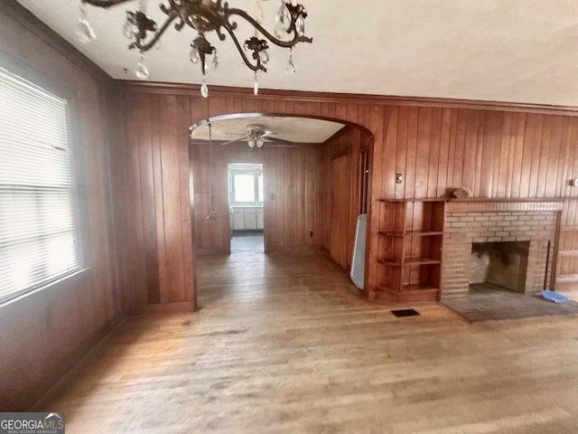 623 Mcdonald St, Waycross, GA 31503 - unfurnished living room with arched walkways, wooden walls, wood finished floors, ceiling fan, and a fireplace