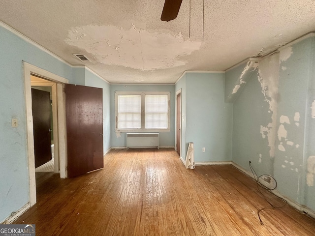 623 Mcdonald St, Waycross, GA 31503 - spare room featuring radiator heating unit, a textured ceiling, crown molding, wood-type flooring, and ceiling fan