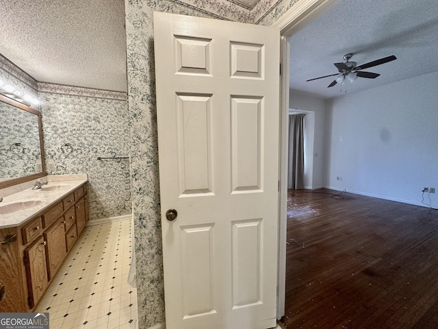 2409 Dorothy St, Waycross, GA 31501 - full bath featuring wallpapered walls, a textured ceiling, baseboards, ceiling fan, and double vanity