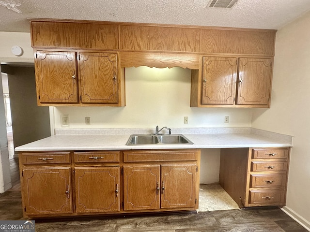 2409 Dorothy St, Waycross, GA 31501 - kitchen featuring a sink, a textured ceiling, dark wood-type flooring, light countertops, and brown cabinetry