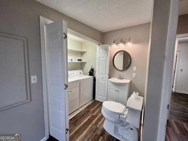 2409 Dorothy St, Waycross, GA 31501 - bathroom featuring washing machine and clothes dryer, wood finished floors, a textured ceiling, toilet, and vanity