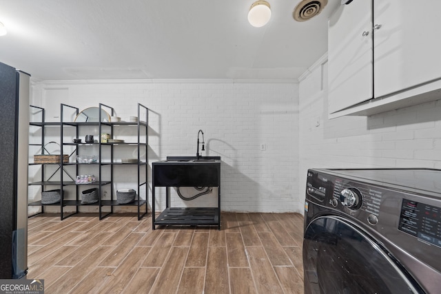 1419 Briarcliff Rd, Macon, GA 31201 - laundry area featuring visible vents, brick wall, wood finished floors, cabinet space, and washer / dryer