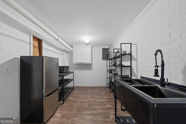 1419 Briarcliff Rd, Macon, GA 31201 - kitchen featuring a sink, freestanding refrigerator, white cabinetry, brick wall, and wood tiled floor