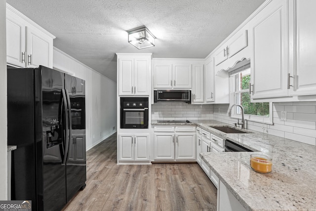 851 Rockbridge Rd SW, Lilburn, GA 30047 - kitchen with a sink, light wood-type flooring, black appliances, backsplash, and white cabinets