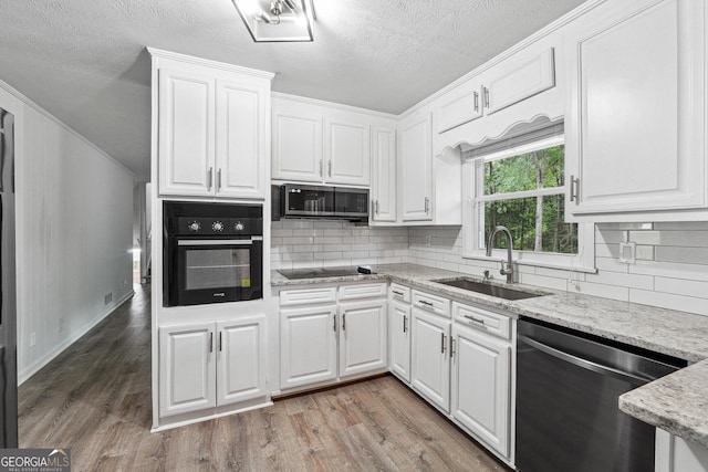 851 Rockbridge Rd SW, Lilburn, GA 30047 - kitchen with black appliances, white cabinetry, light wood-style floors, and a sink