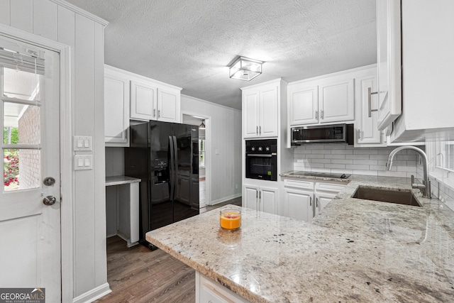 851 Rockbridge Rd SW, Lilburn, GA 30047 - kitchen featuring tasteful backsplash, light stone counters, black appliances, a sink, and white cabinetry