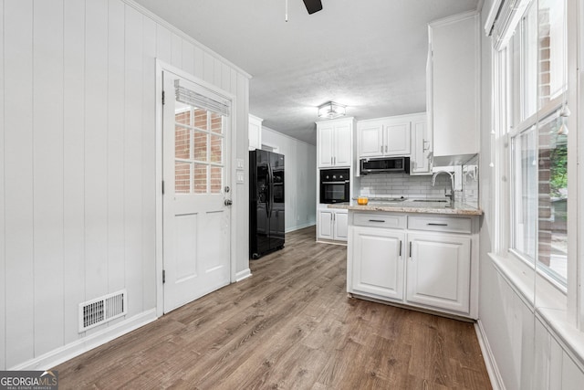 851 Rockbridge Rd SW, Lilburn, GA 30047 - kitchen with white cabinets, a sink, visible vents, black appliances, and light wood-type flooring