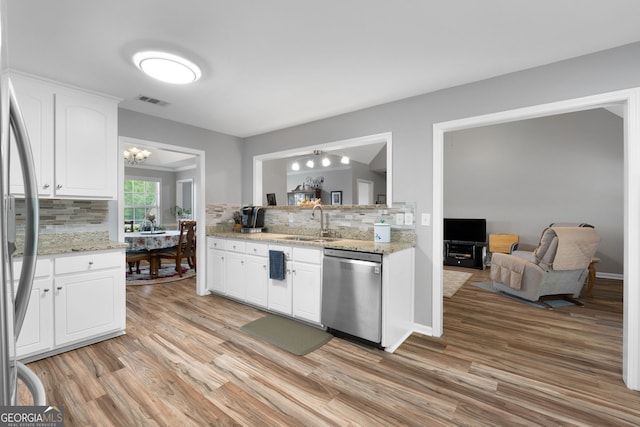 kitchen with appliances with stainless steel finishes, decorative backsplash, light wood-style flooring, and a sink