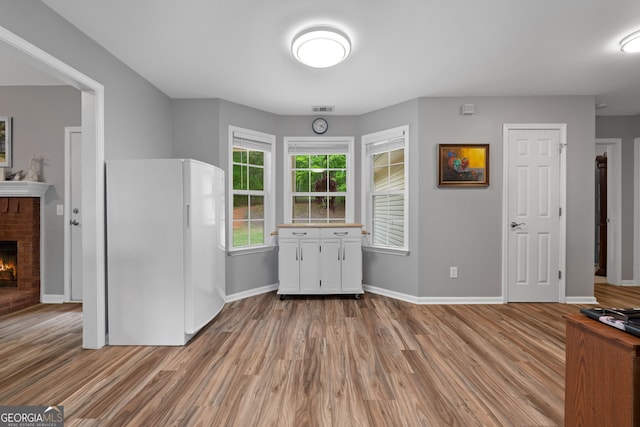 kitchen with a fireplace, light wood-style floors, and freestanding refrigerator