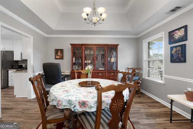 dining area with a raised ceiling, visible vents, dark wood finished floors, and a notable chandelier