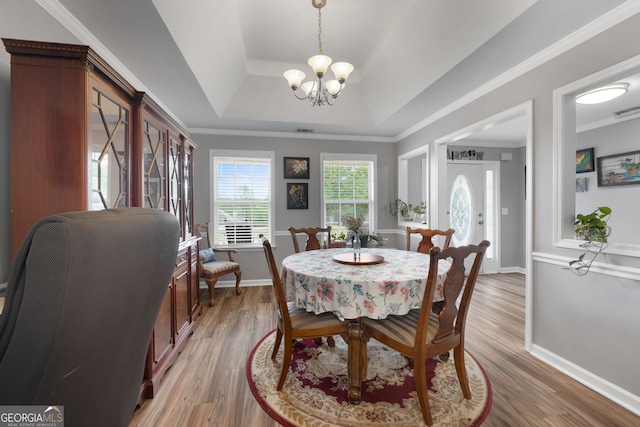 dining space featuring light wood-style floors, baseboards, a notable chandelier, crown molding, and a tray ceiling