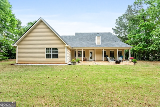 back of house featuring a yard, a patio area, and a shingled roof