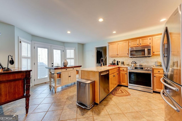 kitchen with recessed lighting, a peninsula, backsplash, appliances with stainless steel finishes, and french doors