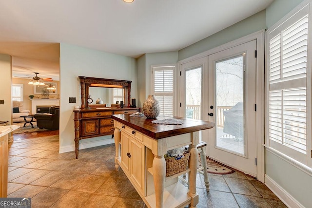 kitchen featuring a fireplace, wooden counters, ceiling fan, and plenty of natural light