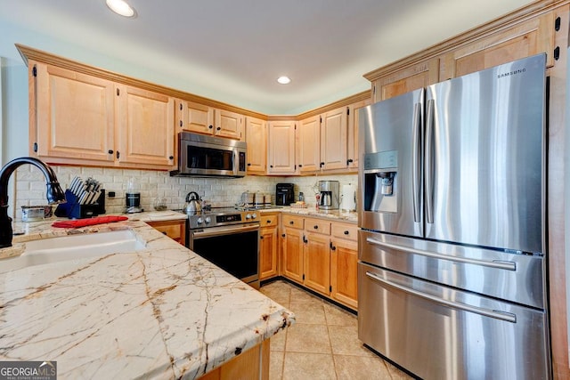 kitchen featuring light brown cabinetry, backsplash, appliances with stainless steel finishes, and a sink