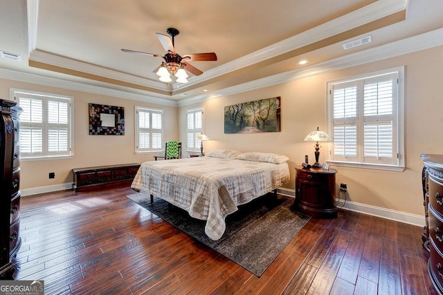 bedroom with hardwood / wood-style floors, baseboards, visible vents, a raised ceiling, and crown molding