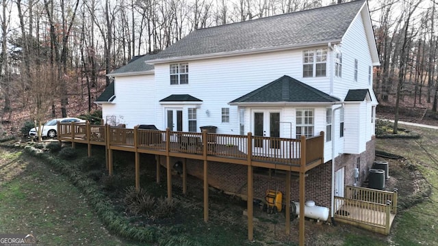 back of house featuring central AC unit, french doors, roof with shingles, and a deck