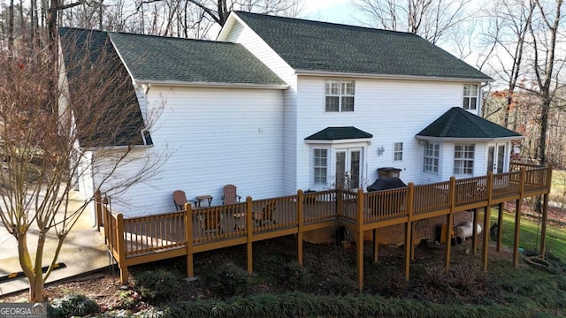 rear view of property with a wooden deck, a shingled roof, and french doors