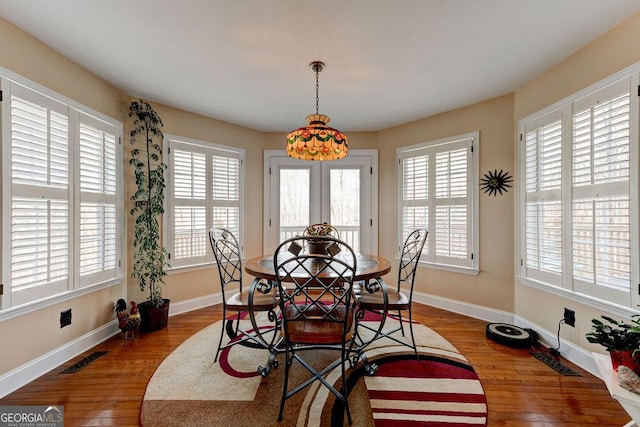 dining space with wood finished floors, visible vents, and baseboards