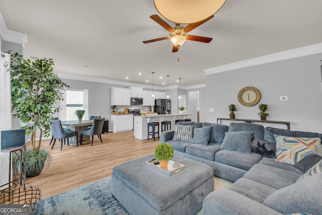 living room with crown molding, recessed lighting, ceiling fan, and light wood-type flooring