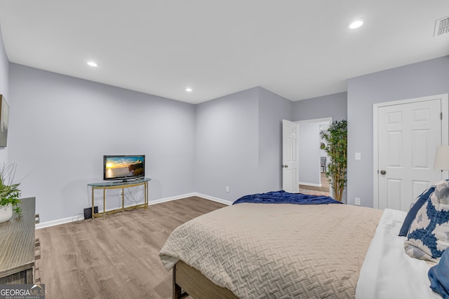 bedroom with baseboards, recessed lighting, wood finished floors, and visible vents