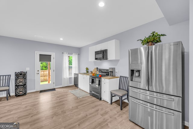 kitchen featuring light countertops, white cabinets, black appliances, and light wood-type flooring