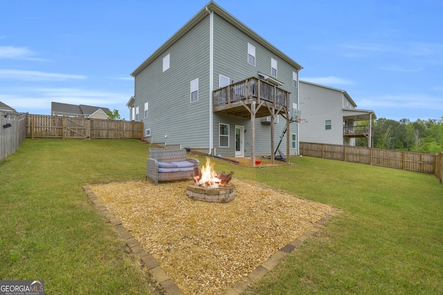 rear view of house featuring a yard, a fire pit, a fenced backyard, and a wooden deck