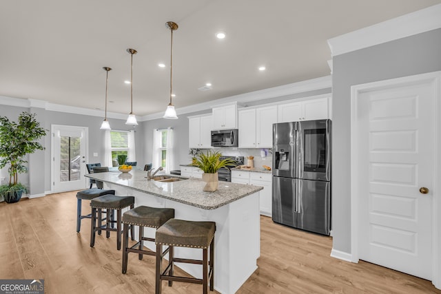 kitchen featuring crown molding, a kitchen island with sink, white cabinets, a sink, and stainless steel appliances