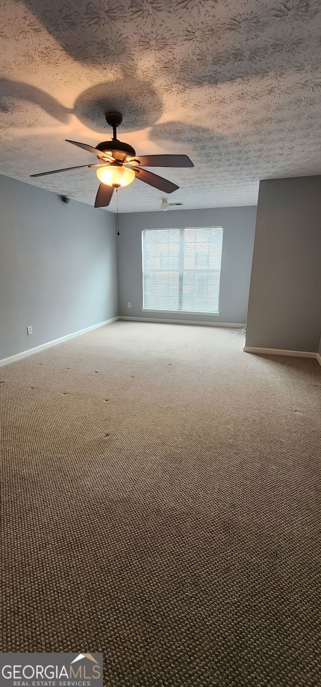 carpeted spare room with baseboards and ceiling fan
