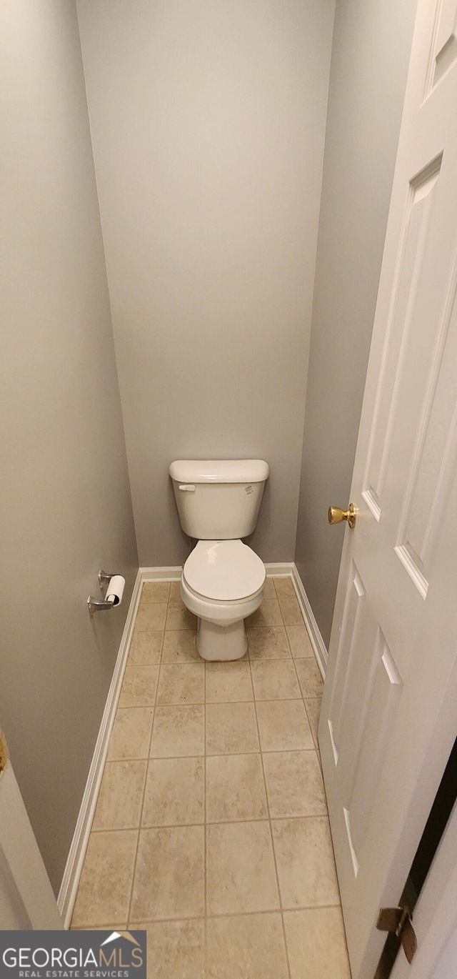 bathroom featuring baseboards, tile patterned floors, and toilet
