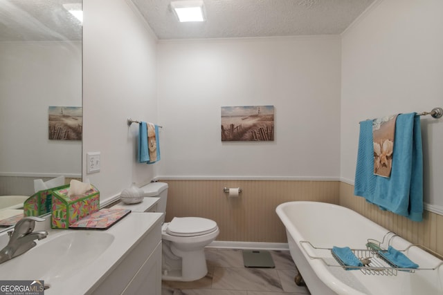 bathroom featuring toilet, vanity, wainscoting, a soaking tub, and a textured ceiling
