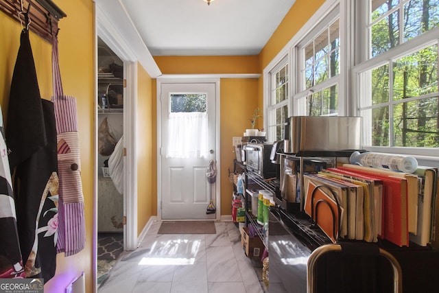 doorway with baseboards, marble finish floor, and a healthy amount of sunlight