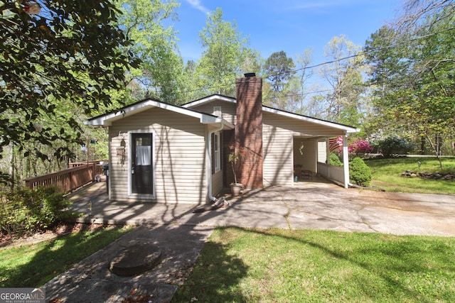 view of front facade with a chimney, a front lawn, concrete driveway, a deck, and a patio