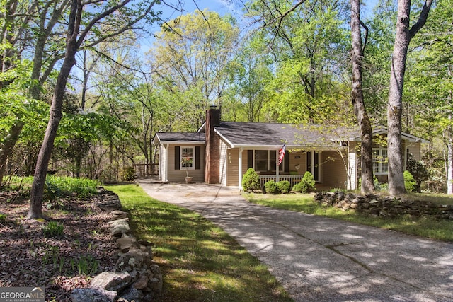 single story home with a chimney, driveway, and covered porch